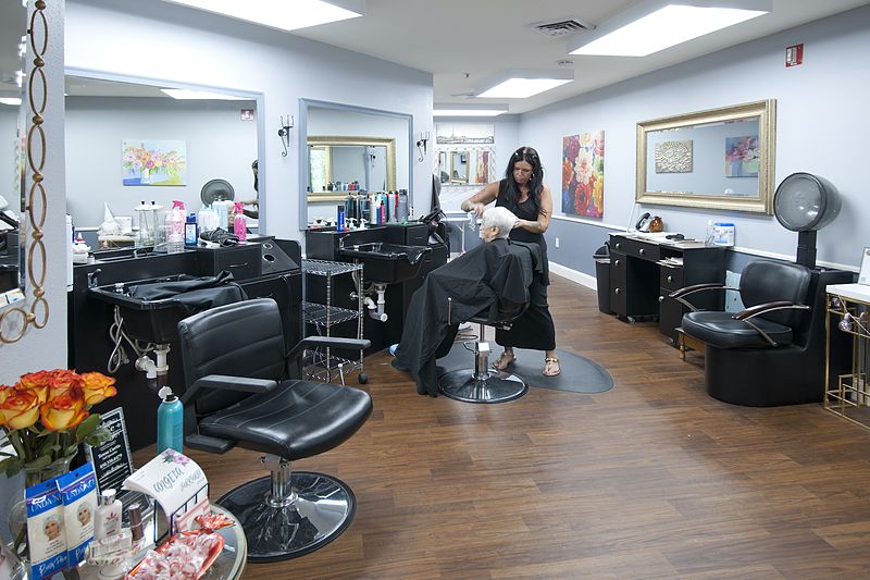 A hair stylist working on a client in a modern and spacious salon.