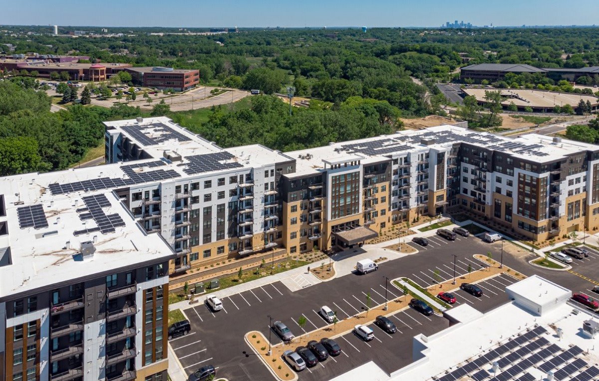 Aerial view of a modern apartment complex with surrounding greenery.