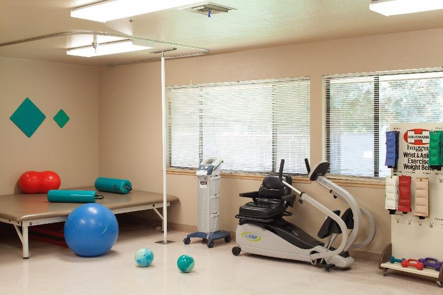 A therapy room equipped with exercise machines, a therapy bed, and fitness balls.