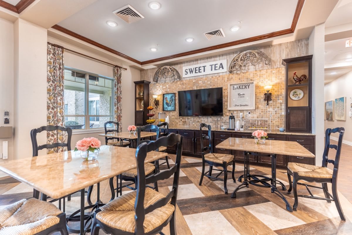 A cozy restaurant interior with neatly arranged tables and chairs, featuring wall art and a television for a welcoming dining experience.