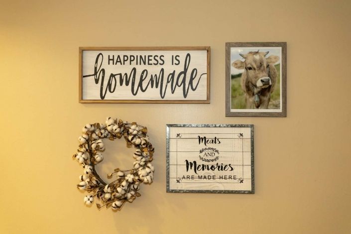 A cozy wall display featuring rustic farmhouse decor with inspirational quotes and a cotton wreath.