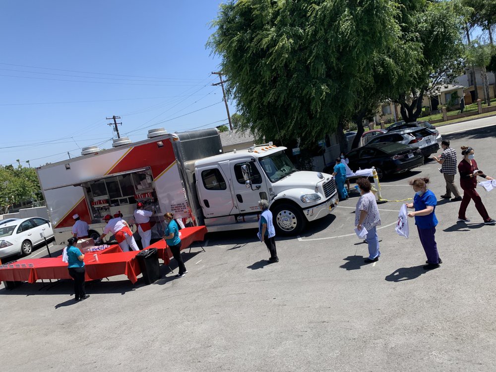 People gather around a food truck on a sunny day.
