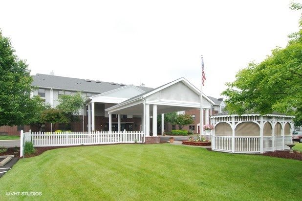 A building entrance with a well-maintained lawn and gazebo.