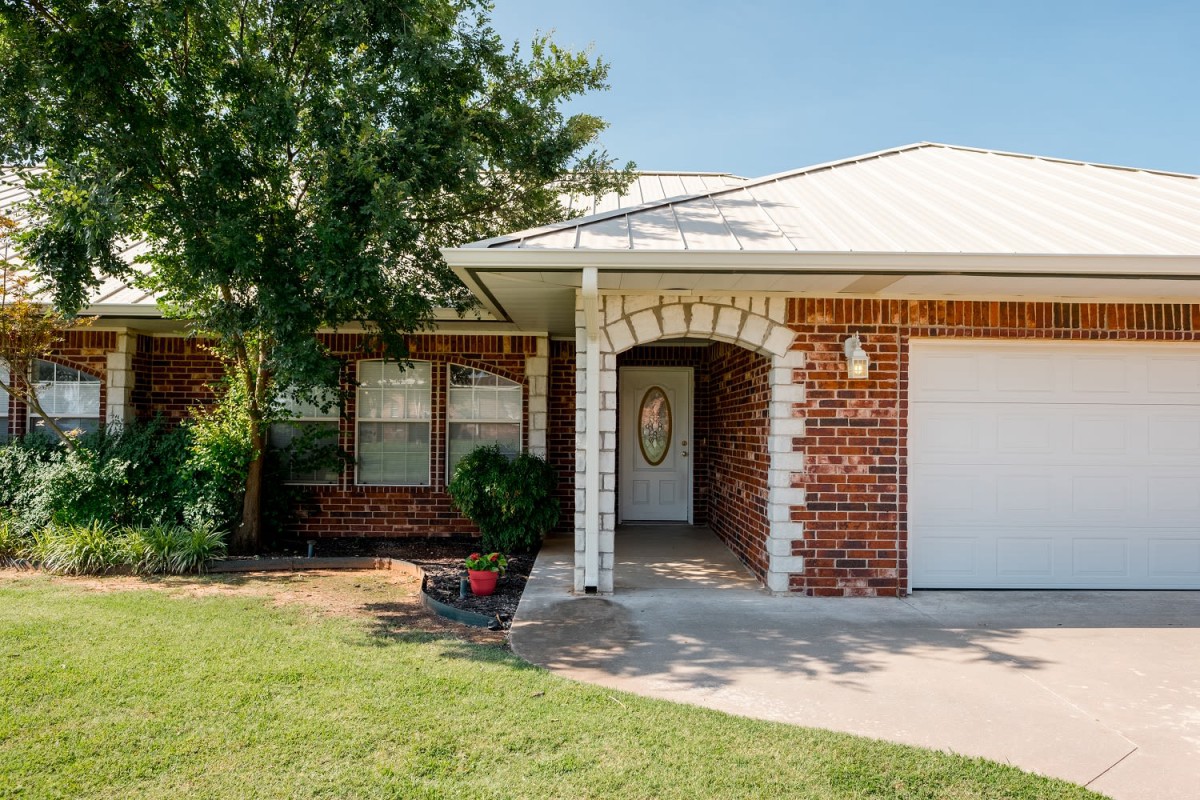 A brick residential house with a garage and front lawn.
