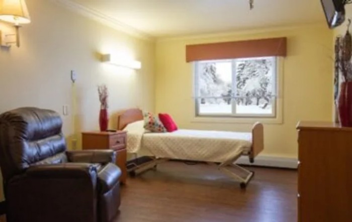 A bright and cozy hospital room with a bed and a chair next to a large window.