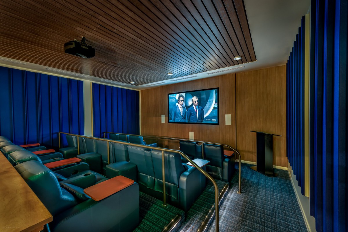 A cozy home theater featuring comfortable seating and a large screen, with a wooden ceiling and curtains for an immersive viewing experience.