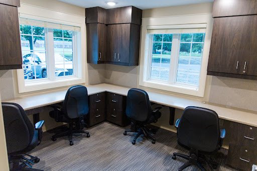 A bright and modern office space featuring two workstations with ergonomic chairs and ample natural light.