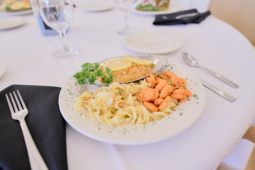 A beautifully arranged plate featuring fettuccine pasta, grilled salmon, cornbread, and a side of green salad.
