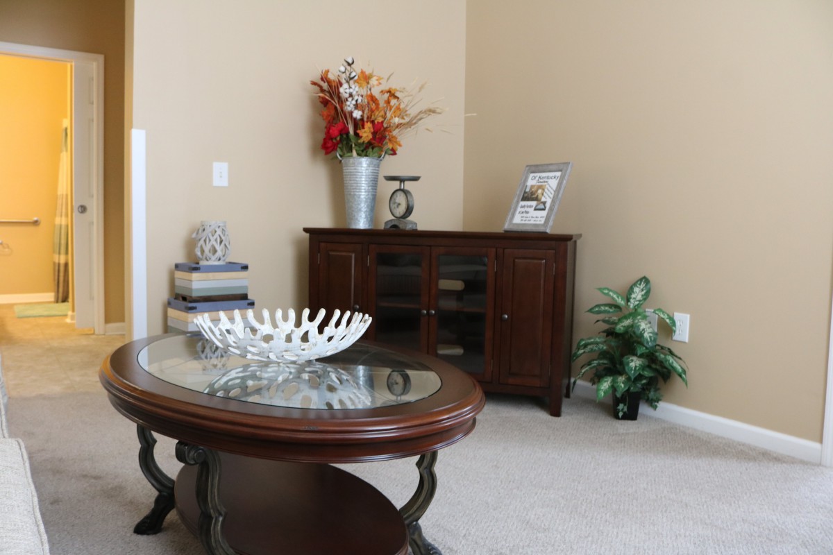 A cozy living room corner featuring a coffee table, decorative items, and a wooden cabinet with a vase of flowers.