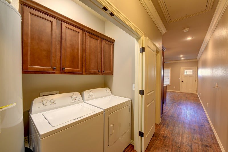 A cozy laundry space with wooden cabinets and appliances in a hallway.