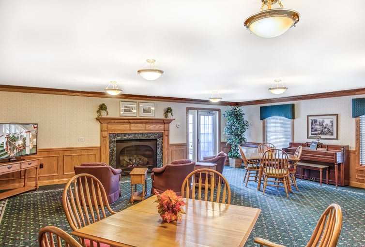 A cozy living and dining area featuring a fireplace, wooden furniture, and warm lighting.