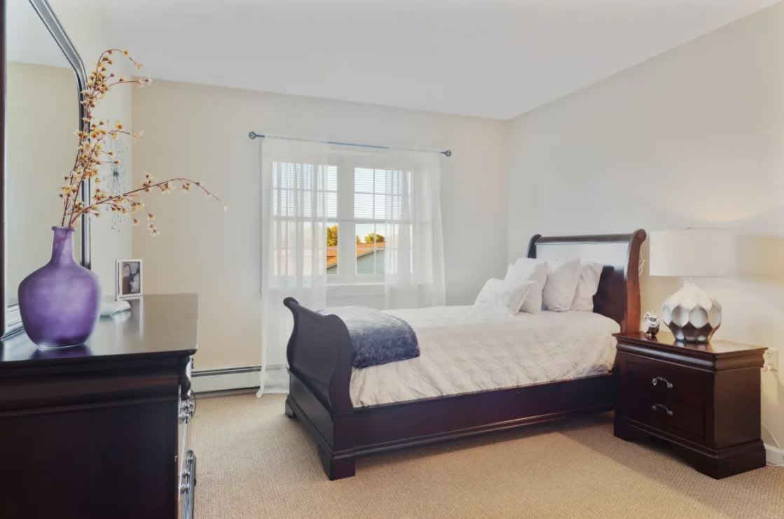 A cozy bedroom with elegant furniture and natural light streaming through the large window.