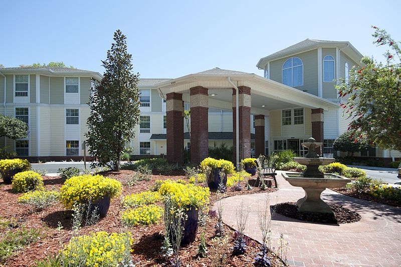 A modern building with a landscaped garden and a fountain at the entrance.