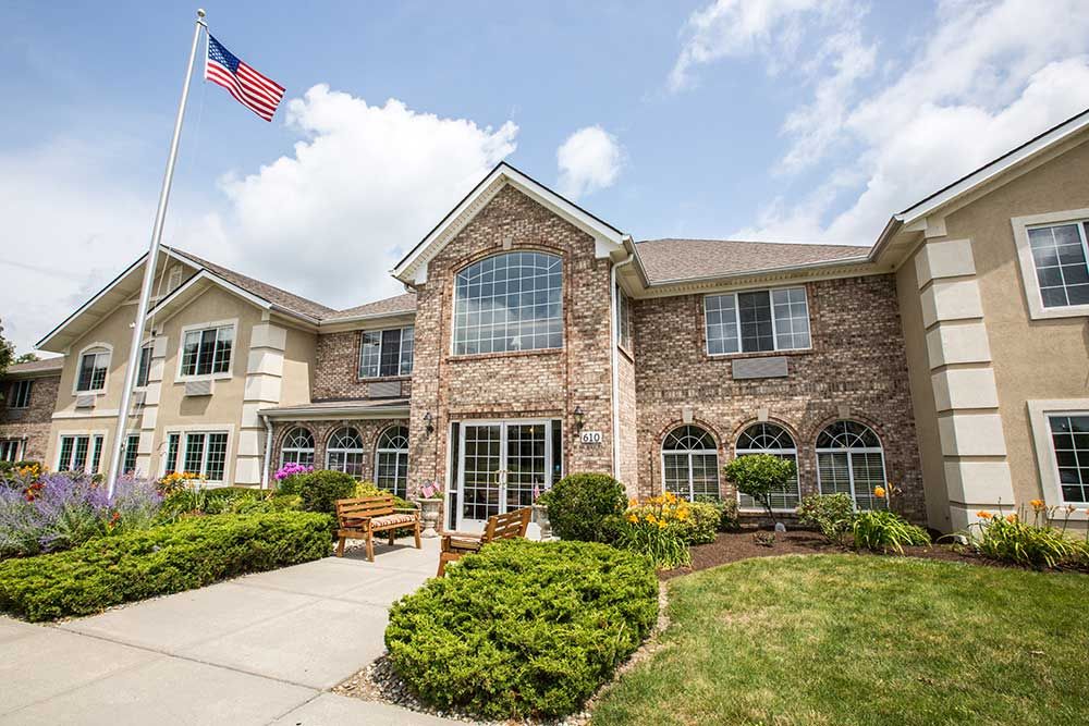 A two-story brick building with well-maintained landscaping and an American flag on display.