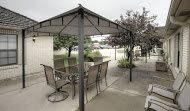 Outdoor gazebo with chairs and a table on a paved surface.
