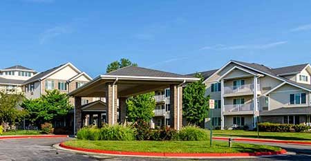 A residential apartment complex with a covered entrance and landscaped surroundings.
