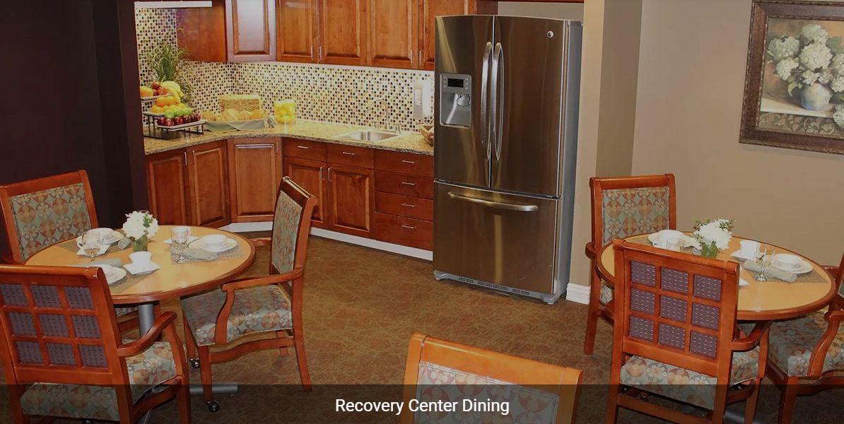 A cozy dining area in a recovery center featuring wooden cabinetry and modern appliances.