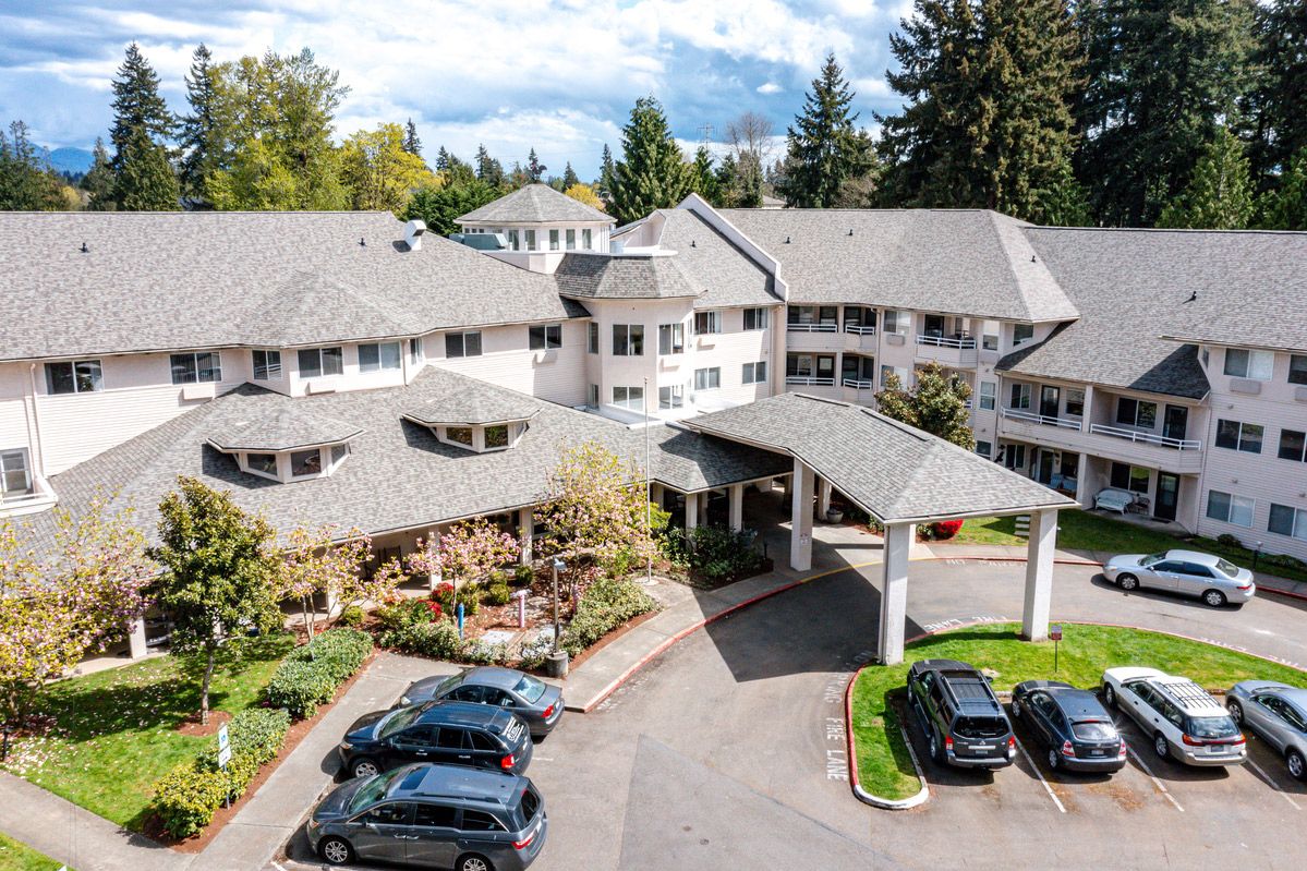 Aerial view of a residential building complex with parked cars and surrounding trees.