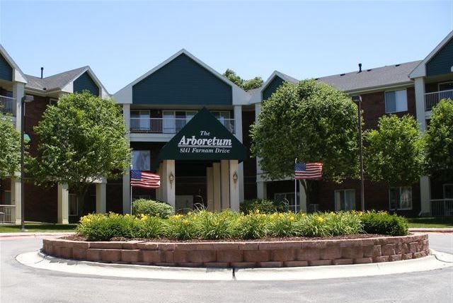 The entrance to an apartment complex surrounded by trees and landscaping.