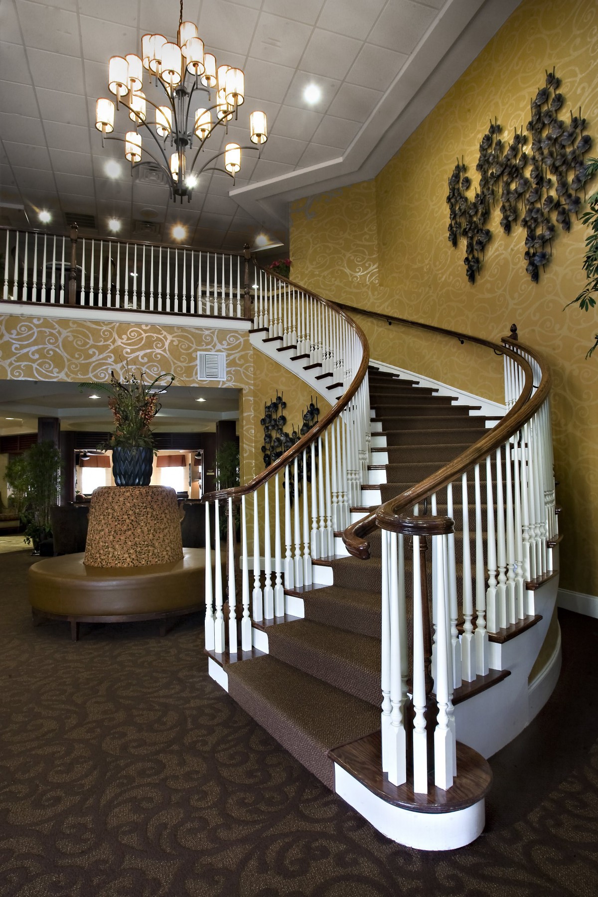 A grand, sweeping staircase in an elegantly decorated lobby with a chandelier.