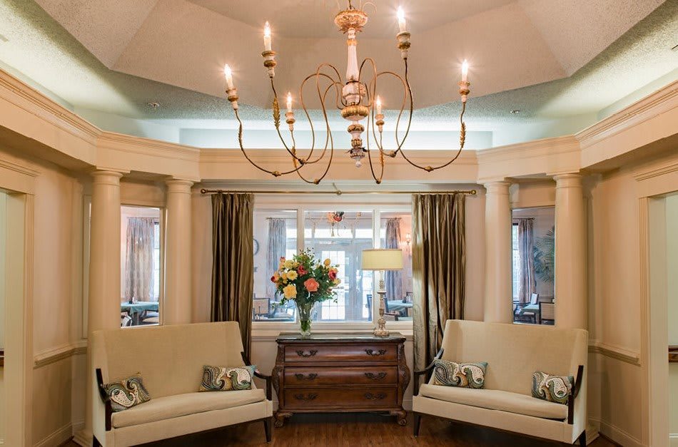 Elegant living room with a central chandelier, twin sofas, and floral decor.