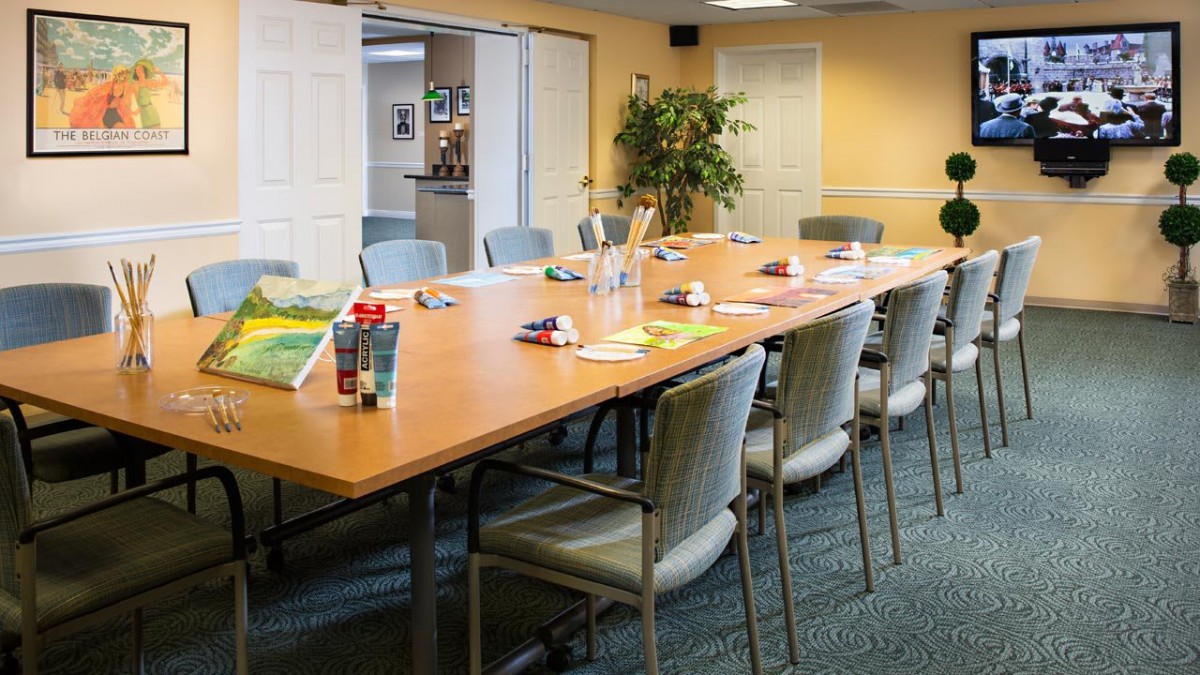 A conference room with a large meeting table, surrounded by chairs and set up with books and notebooks.