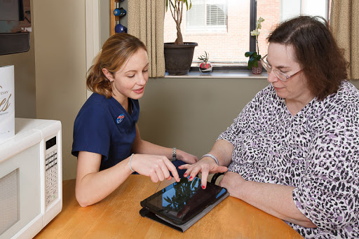 A healthcare professional assists a patient with using a tablet, fostering engagement and learning.