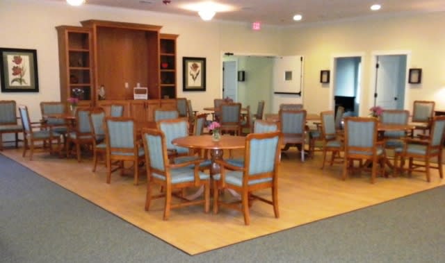 A cozy dining area with wooden tables and chairs, arranged in a spacious room.