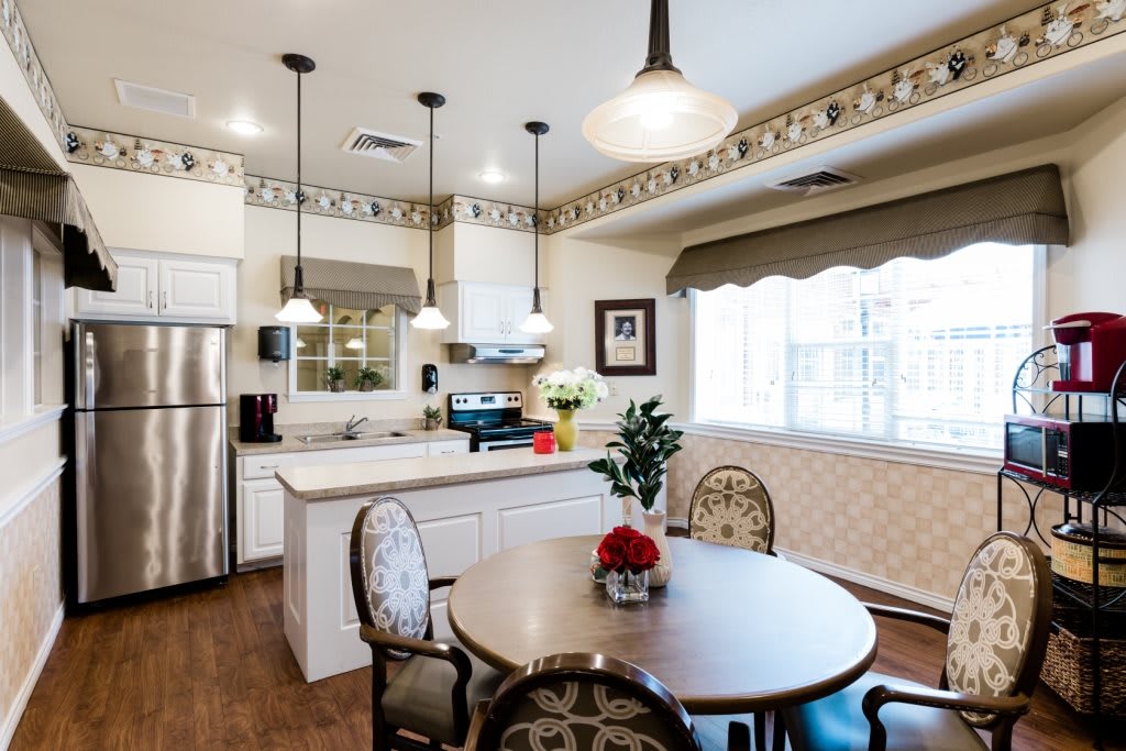 A modern kitchen and dining area featuring white cabinets, stainless steel appliances, and pendant lighting.