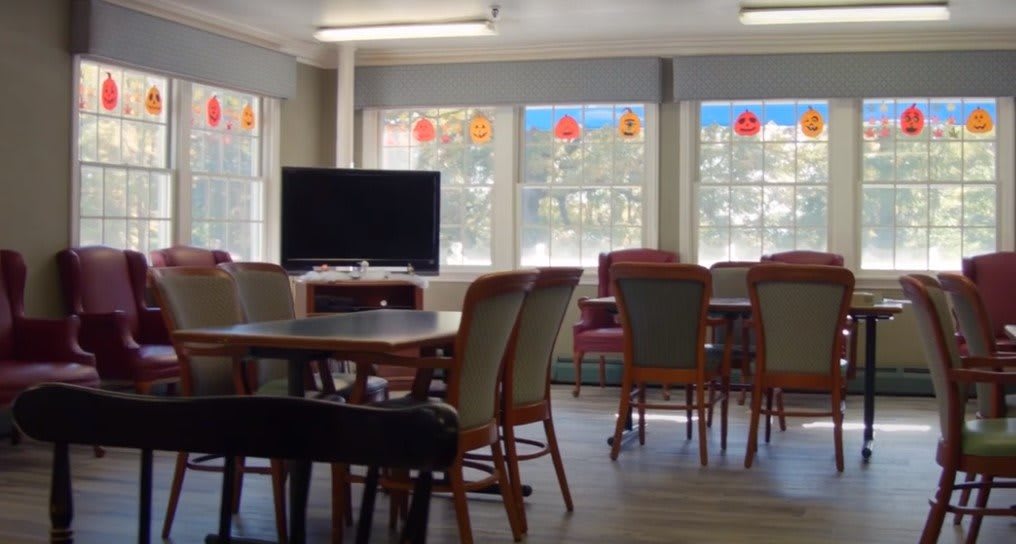 A communal room with tables, chairs, and a television.