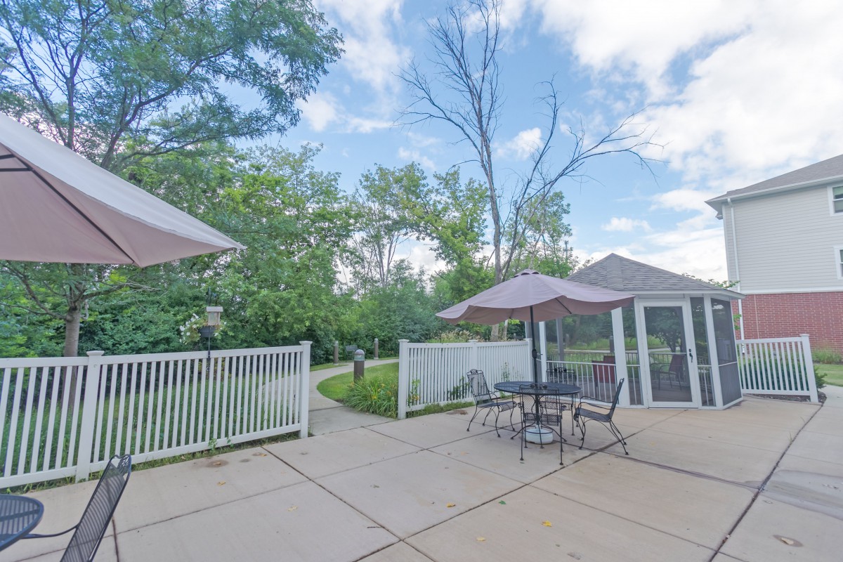 A serene outdoor patio with tables, umbrellas, and lush greenery.