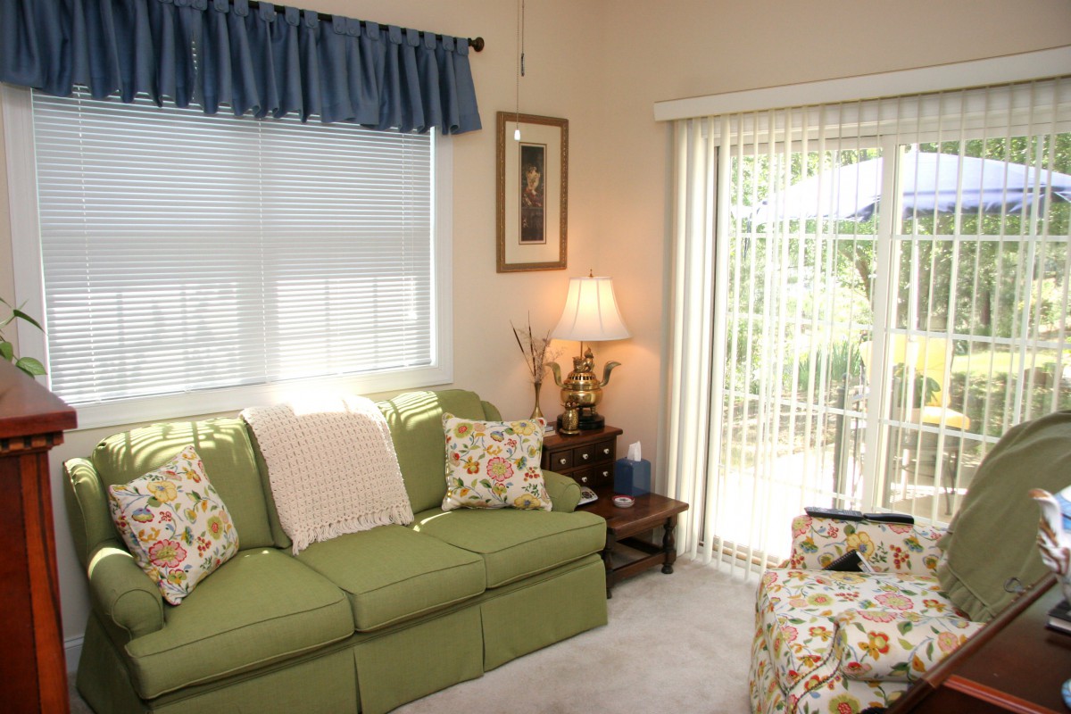 A cozy living room with a green sofa, soft lighting, and large windows.