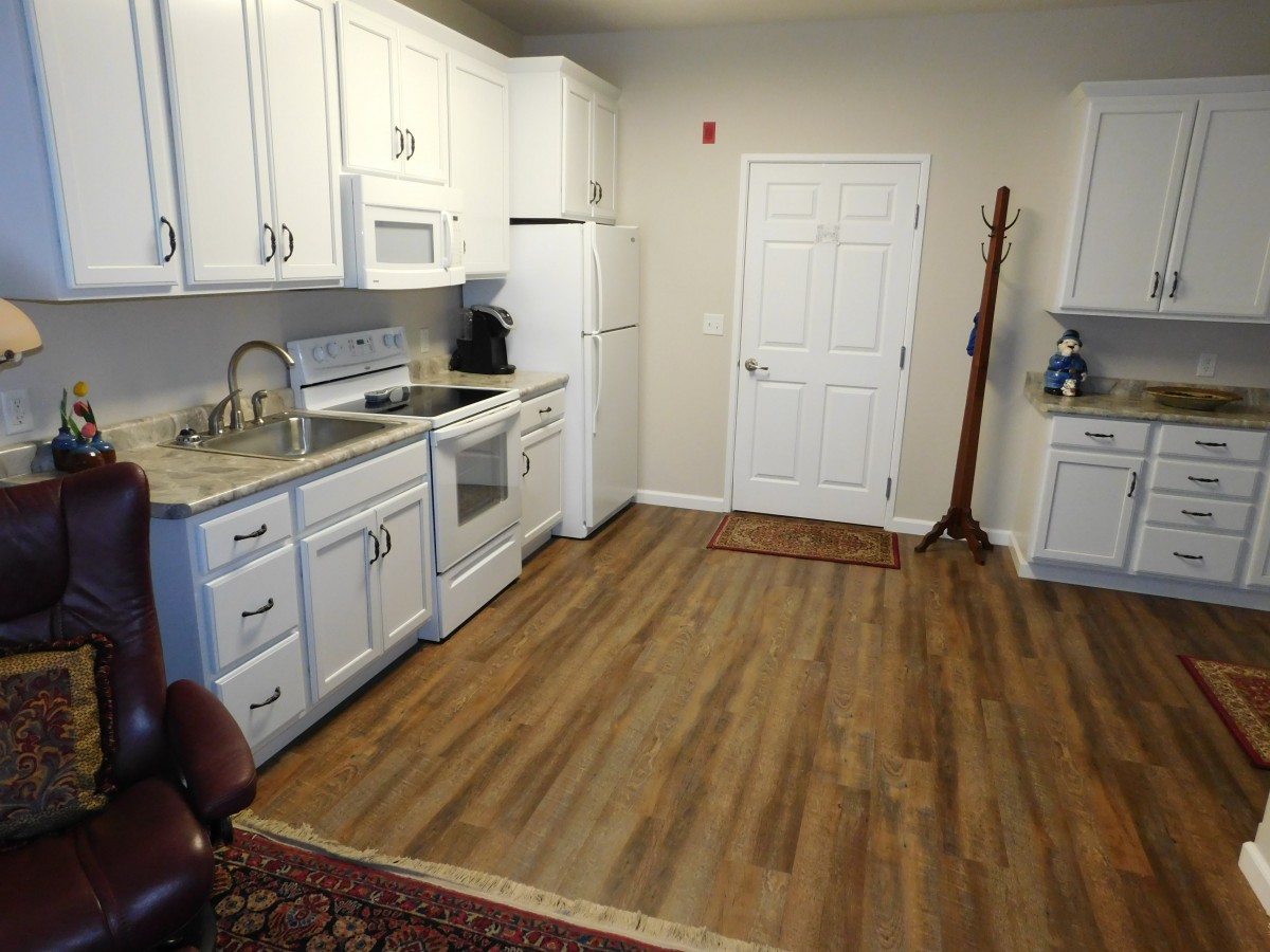 A modern kitchen with white cabinets and a wood floor.