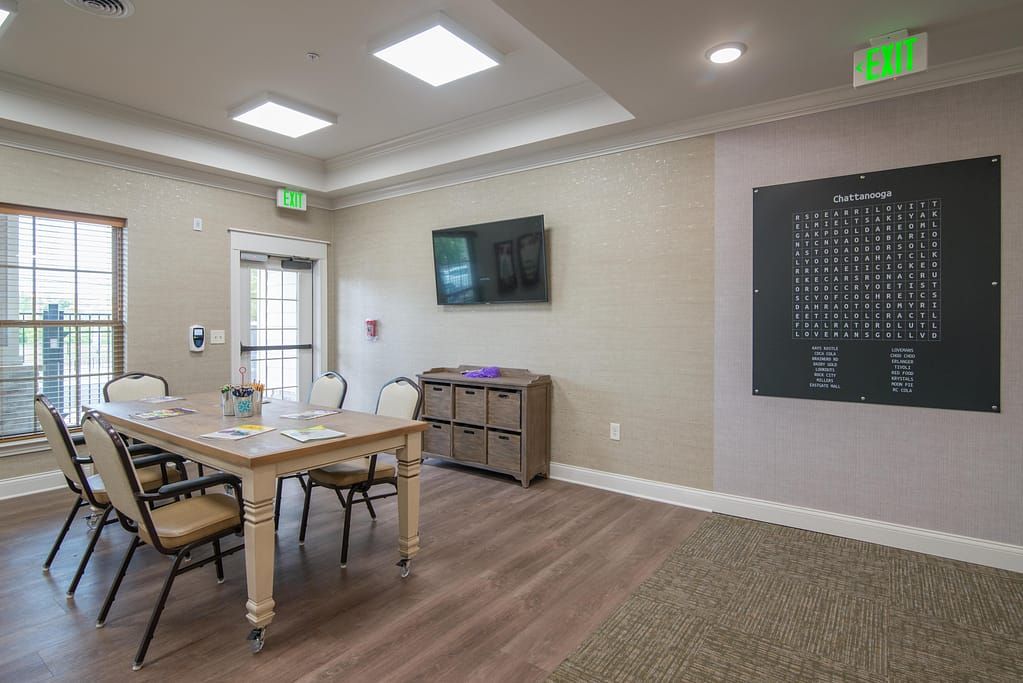 A well-lit conference room with a wooden table, chairs, and a TV screen on the wall.