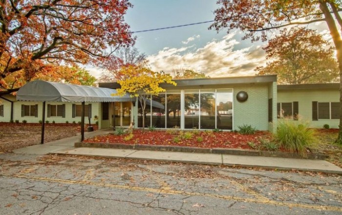 A building with large glass windows surrounded by autumn foliage.