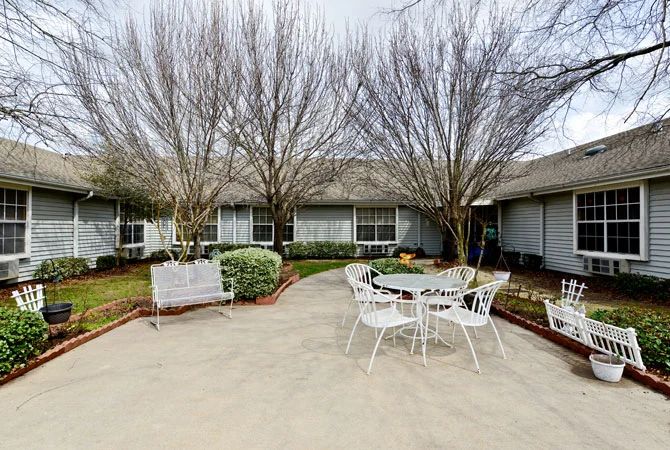A tranquil courtyard with patio furniture and trees, surrounded by a building.