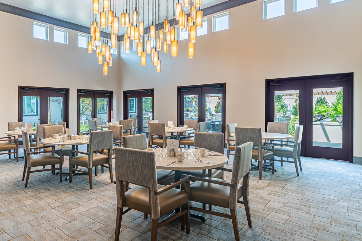 A modern dining area with elegant chandeliers and neatly arranged tables and chairs.