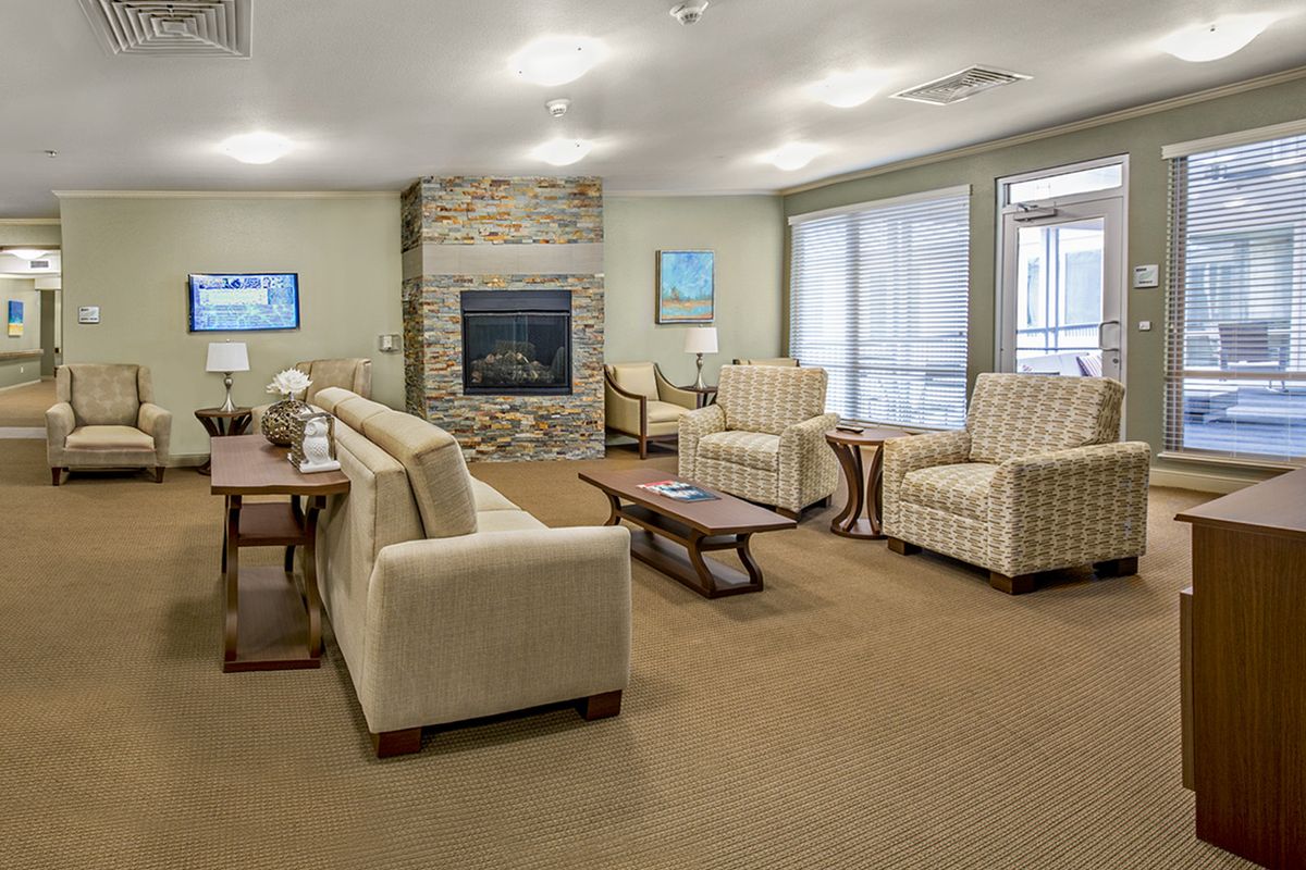 A spacious and well-designed living room featuring comfortable seating, a central fireplace, and large windows allowing natural light.
