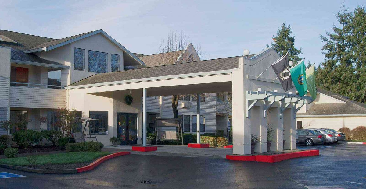A residential building with a covered entrance and landscaped surroundings.