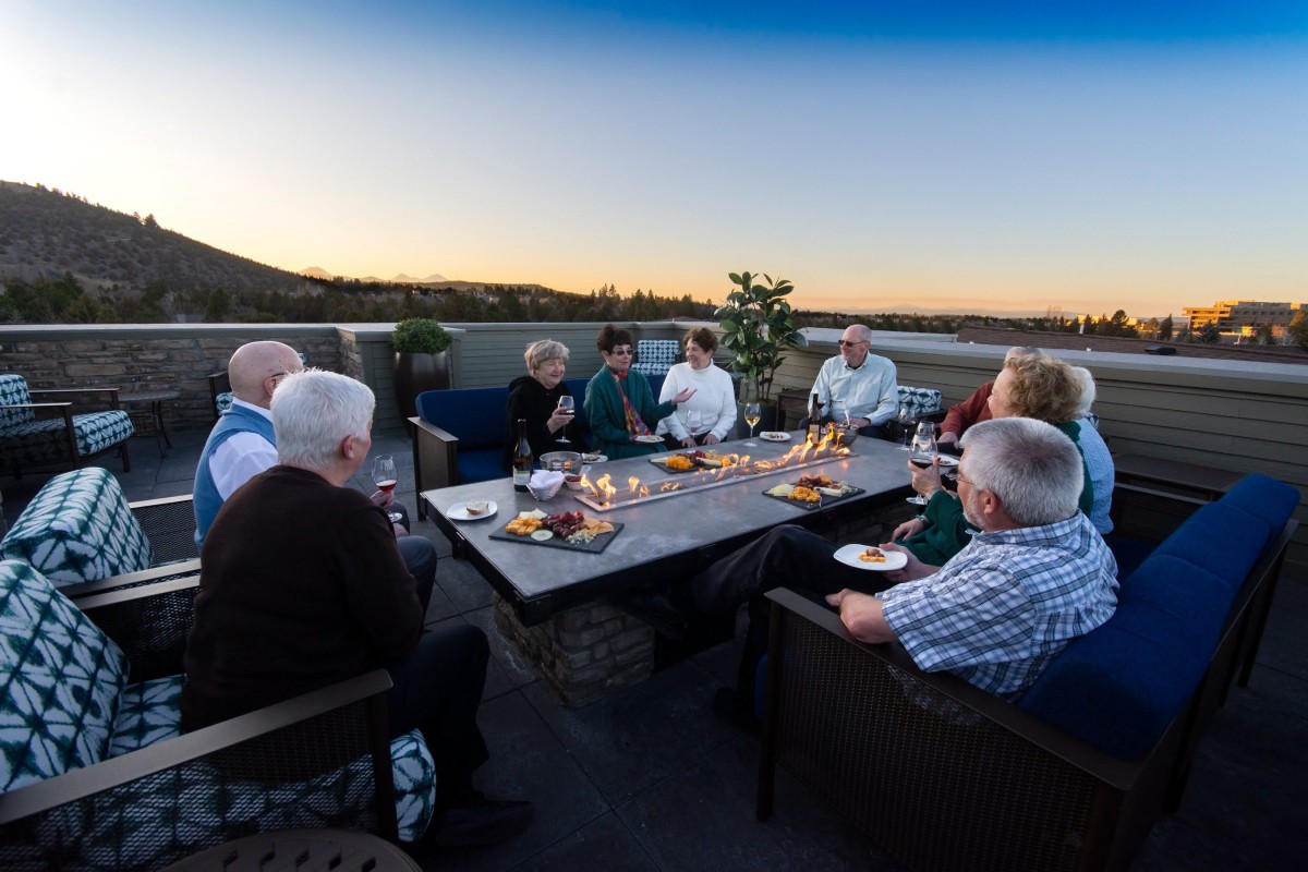 A group of people enjoying an outdoor meal around a table at sunset.