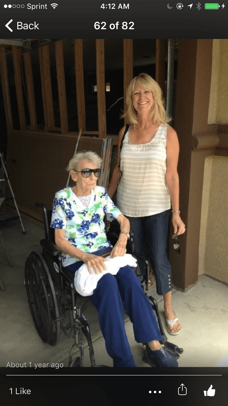 A woman stands beside an elderly person in a wheelchair.