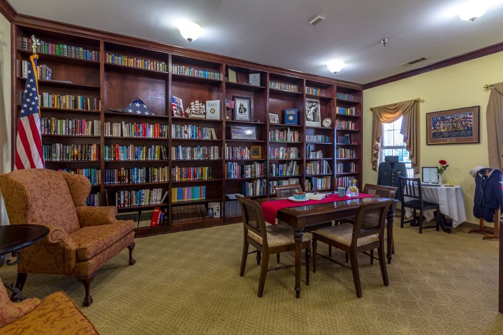 A cozy library with extensive bookshelves and a central table for reading.