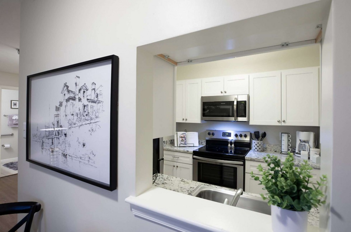 A modern kitchen with white cabinets and sleek appliances, complemented by minimalist decor and framed artwork.