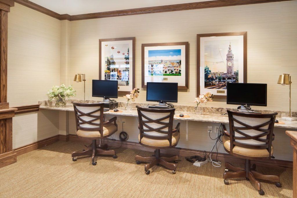A modern office with three computer workstations and decorative wall art.