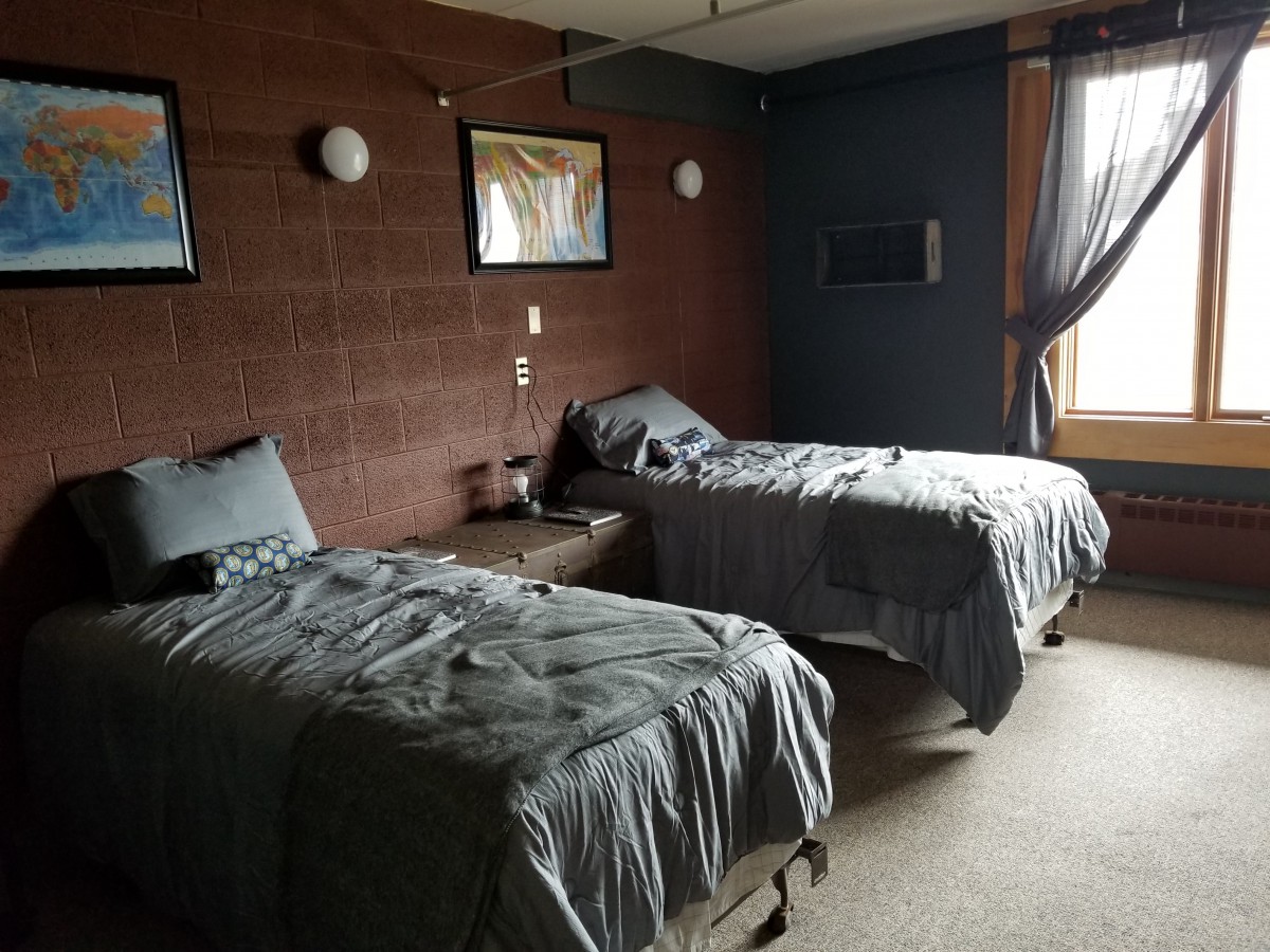 A cozy bedroom with two neatly made beds, adorned with simple decor and a window letting in natural light.