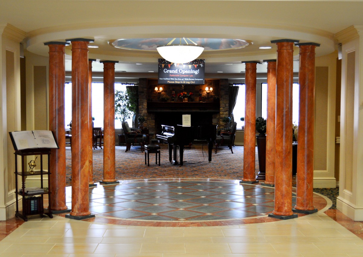 A luxurious lobby with polished columns and a grand piano at the center.