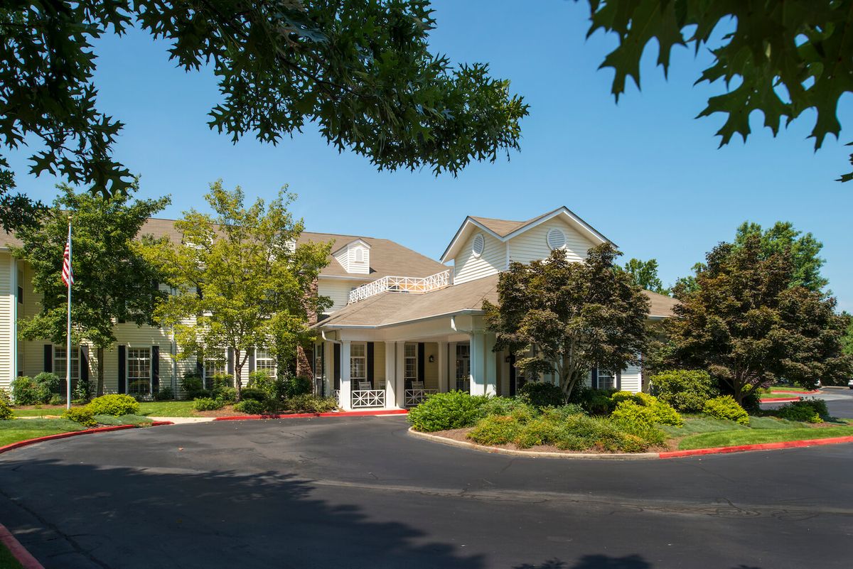 A building entrance surrounded by trees and landscaping on a sunny day.