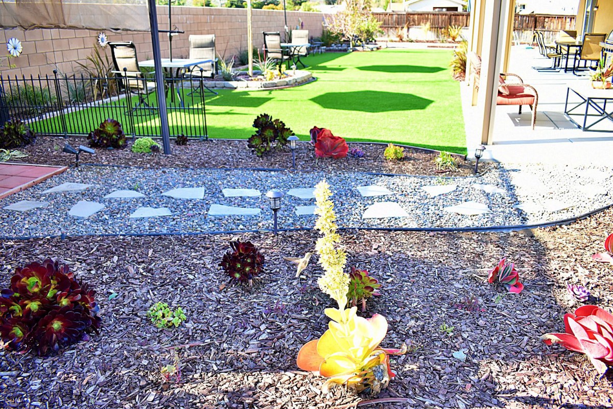 A landscaped garden with a gravel path, succulents, and patio furniture.