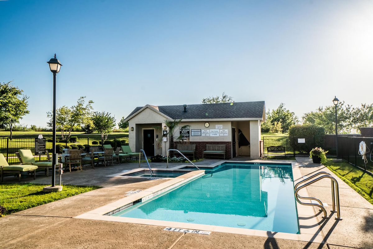 A small outdoor swimming pool beside a building under a clear blue sky.