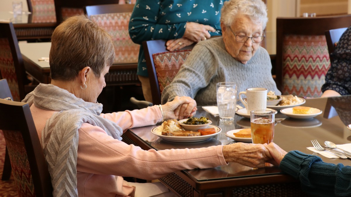 Elderly individuals sharing a meal together at a dining table.